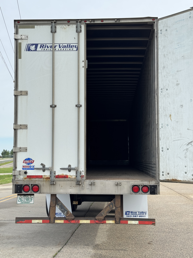 Truck trailer rear with open roll-up door showing interior. River Valley logo on left door and taillights visible.