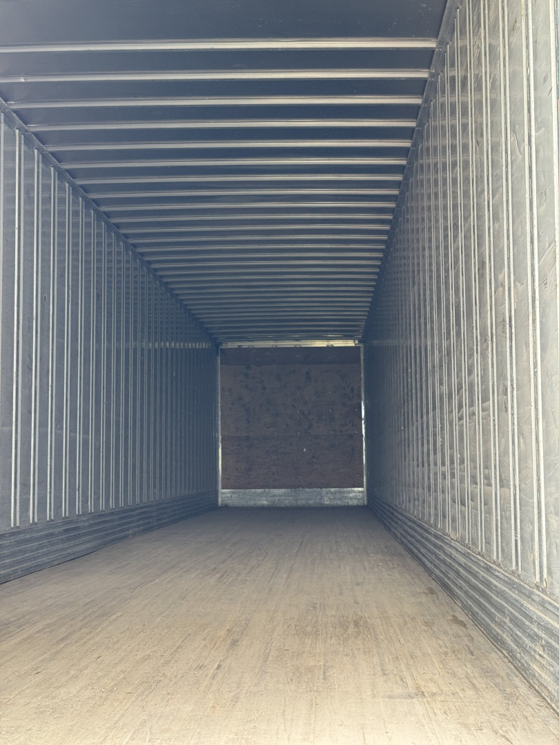 TrailER interior showing empty box with metal ribs and wooden floor, viewed from one end toward the far end.