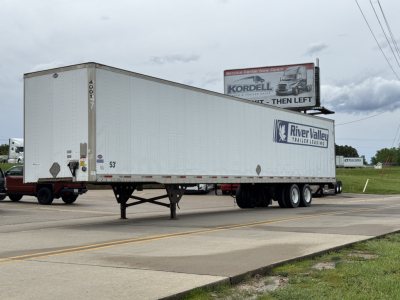 Trailer showing River Valley trailers graphic, Utility 4000DX box trailer with landing gear and dual rear axles, side markings including 53' length and model number.