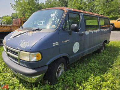 Dodge Ram 350 van exterior with faded blue paint and a rusted tan roof, passenger side view, old white circular decal on door, worn windows, front bumper intact.