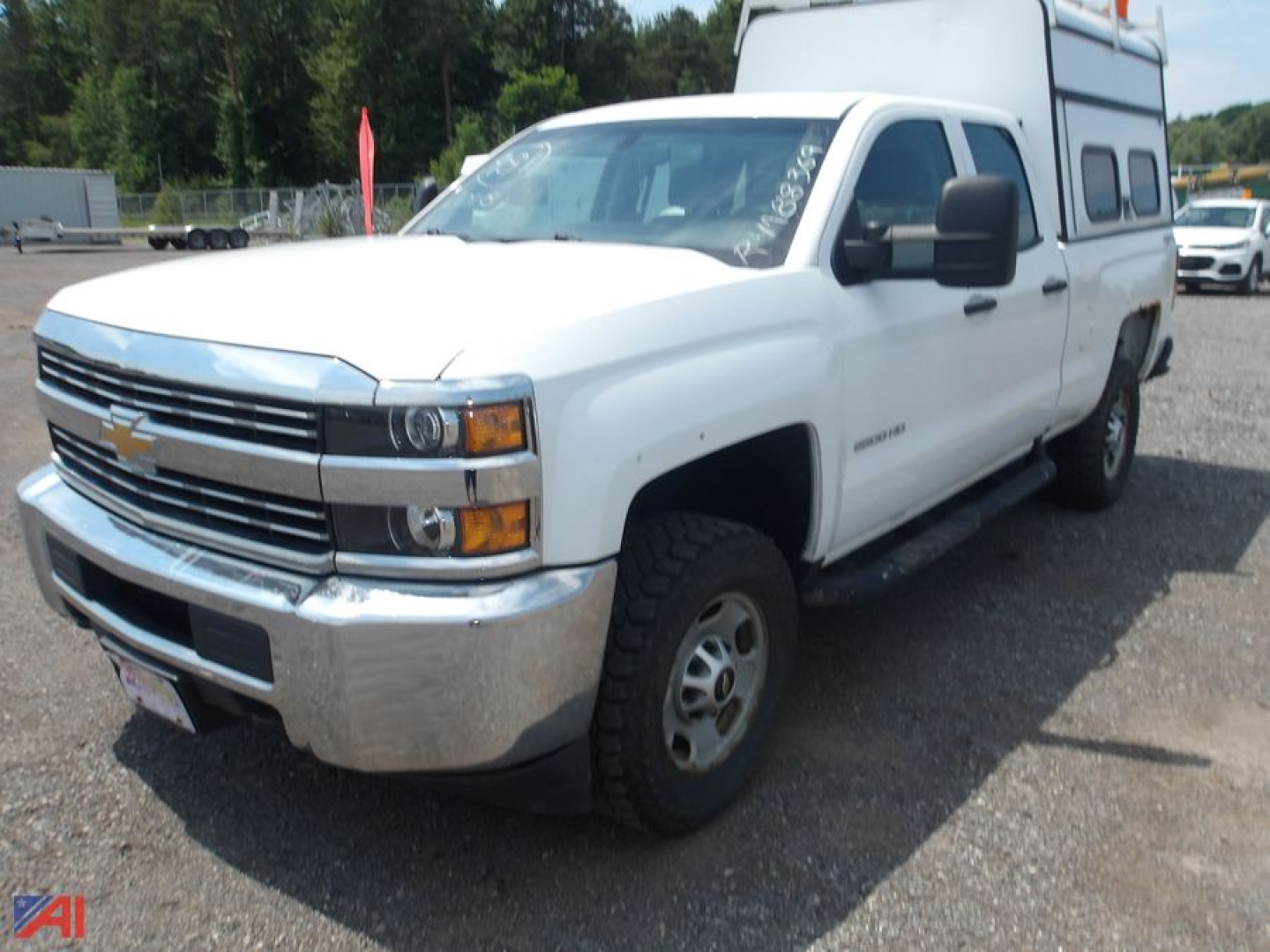 Chevrolet Silverado 2500HD pickup with cap, white exterior, quad cab, 4x4, front view showing chrome grille and bumper.