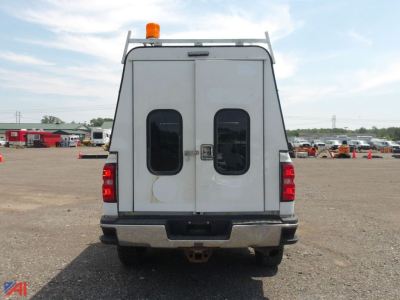 Rear view of a white 2018 Chevrolet Silverado 2500HD quad cab pickup with cap, taillights, rear doors, and orange beacon on top.
