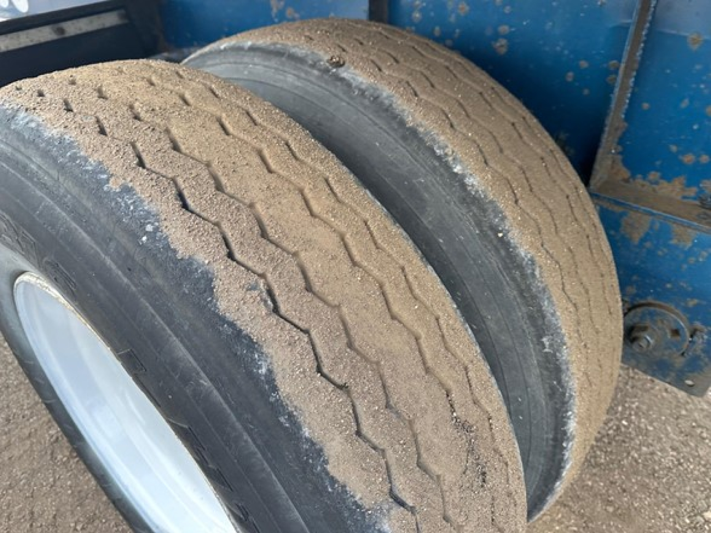 Great Dane Freedom LT trailer wheel well showing dual rear tires with tread wear and sand/dust on tires.