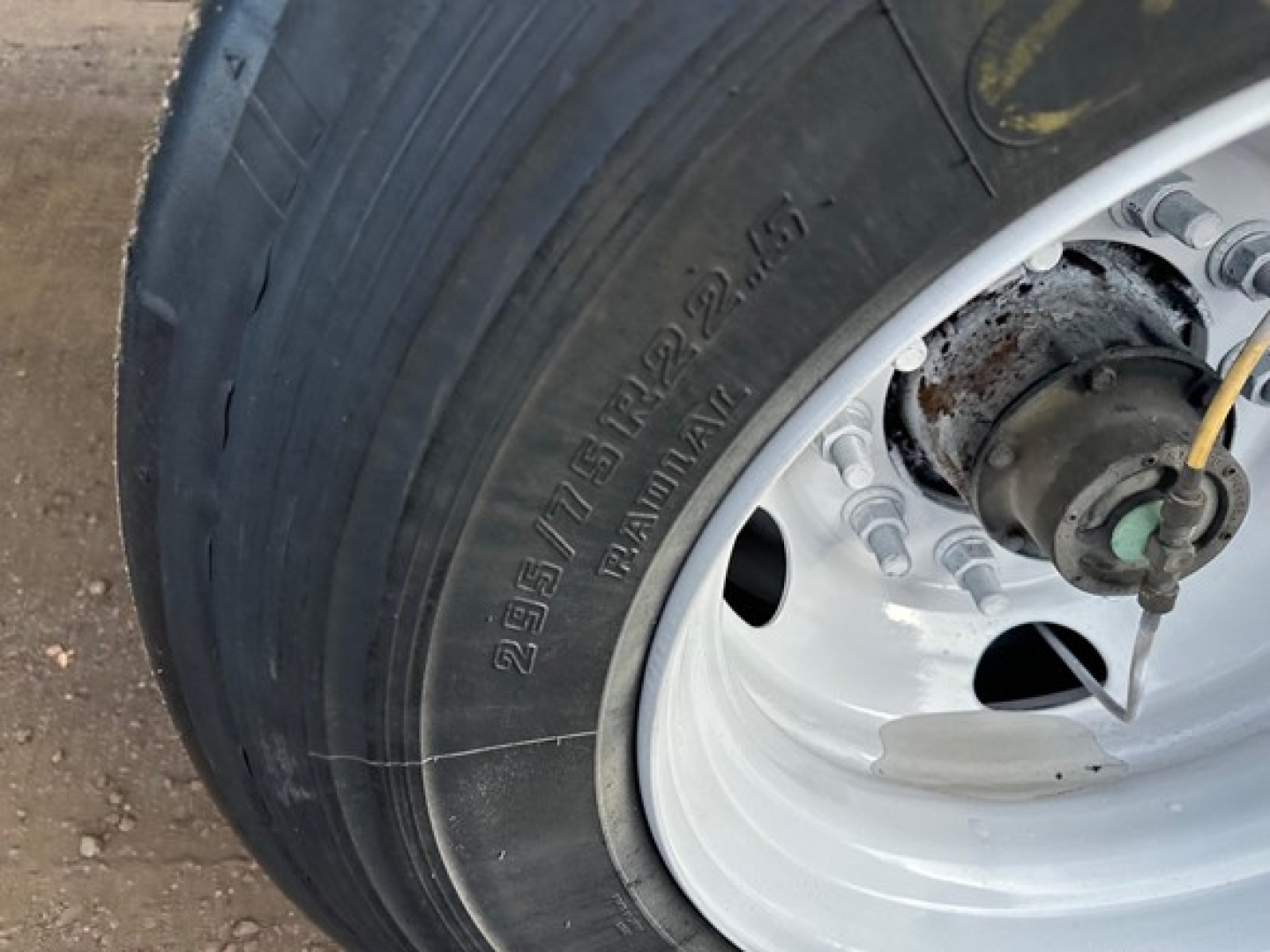 Great Dane trailer wheel showing tire and hub with metallic rim and bolts; partial view of suspension components.