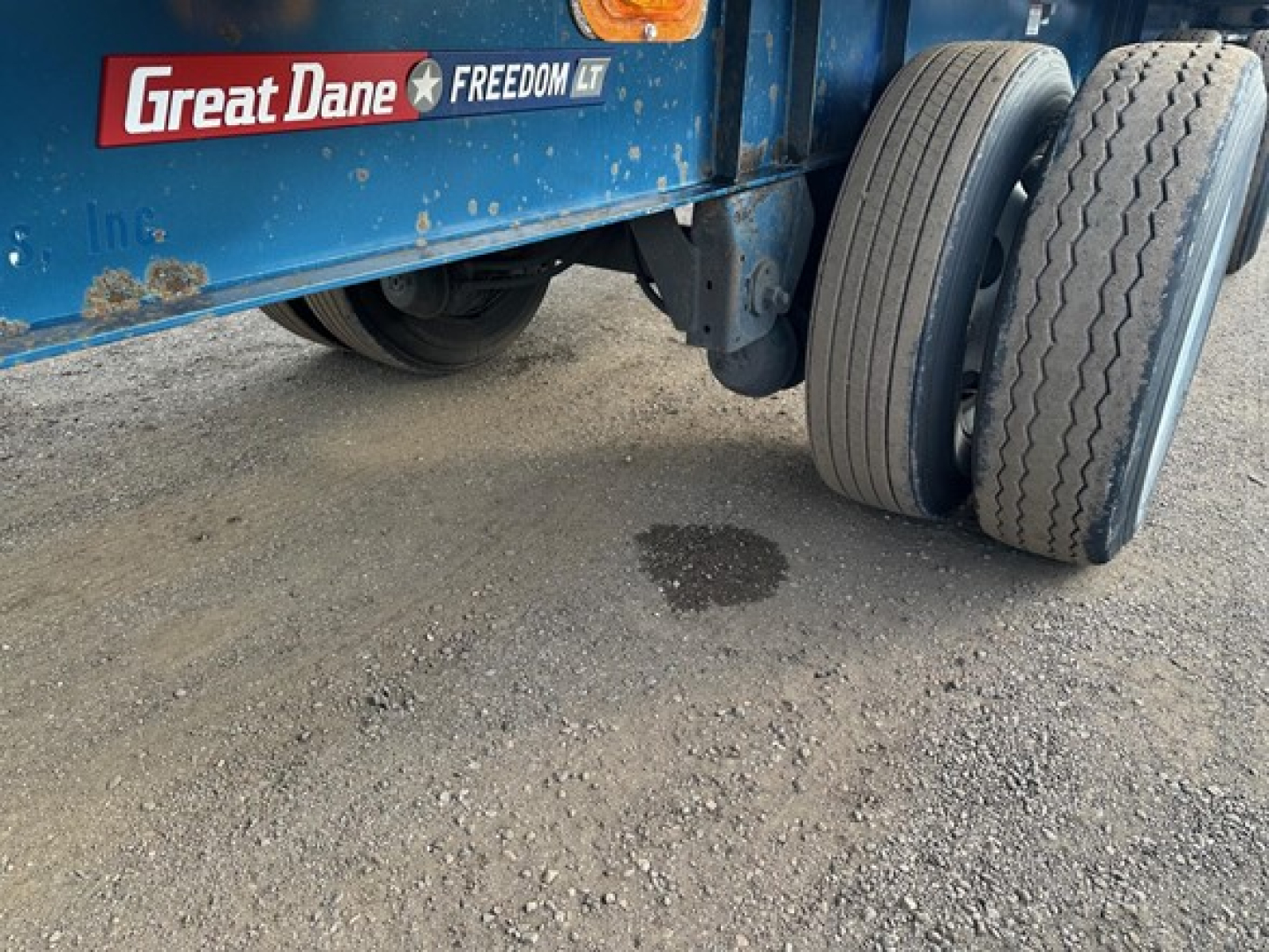 Great Dane Freedom LT trailer wheel area showing dual rear tires and blue painted frame with Great Dane Freedom LT logo and sticker.