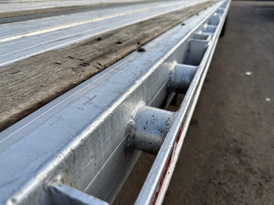 Flatbed trailer edge with metal stake pockets and wooden planks showing on 2014 Great Dane Freedom LT.