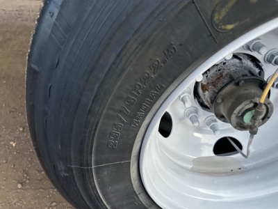 Great Dane trailer wheel showing tire and hub with metallic rim and bolts; partial view of suspension components.