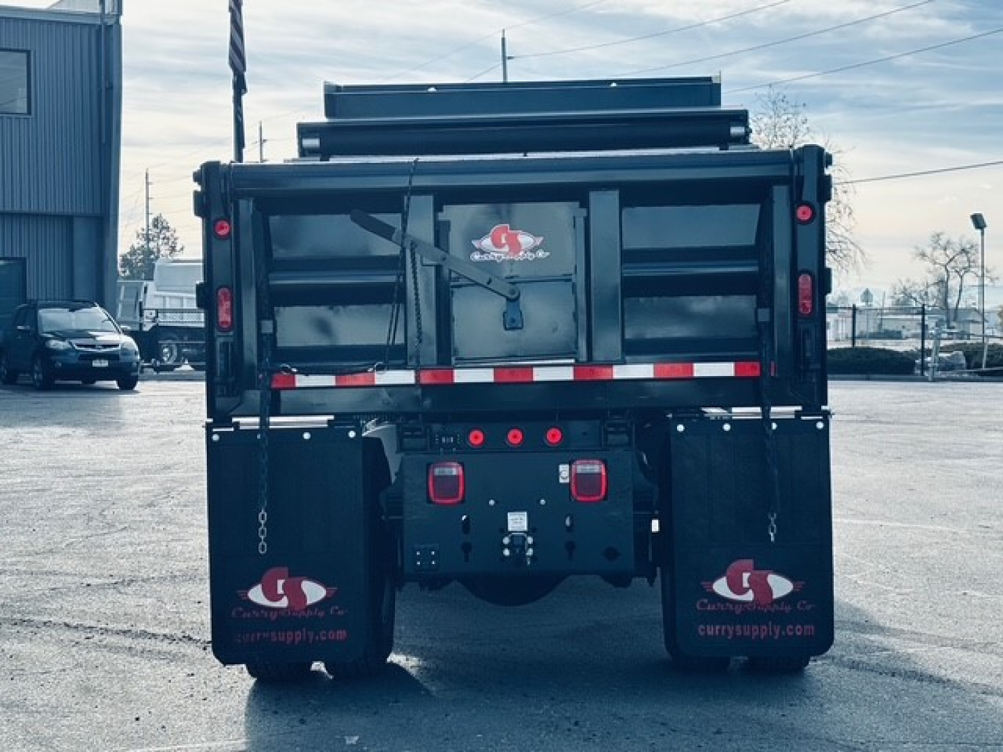 Rear view of a new 2025 Mack MD6 dump truck showing dump bed, tailgate, and mud flaps with company logos.