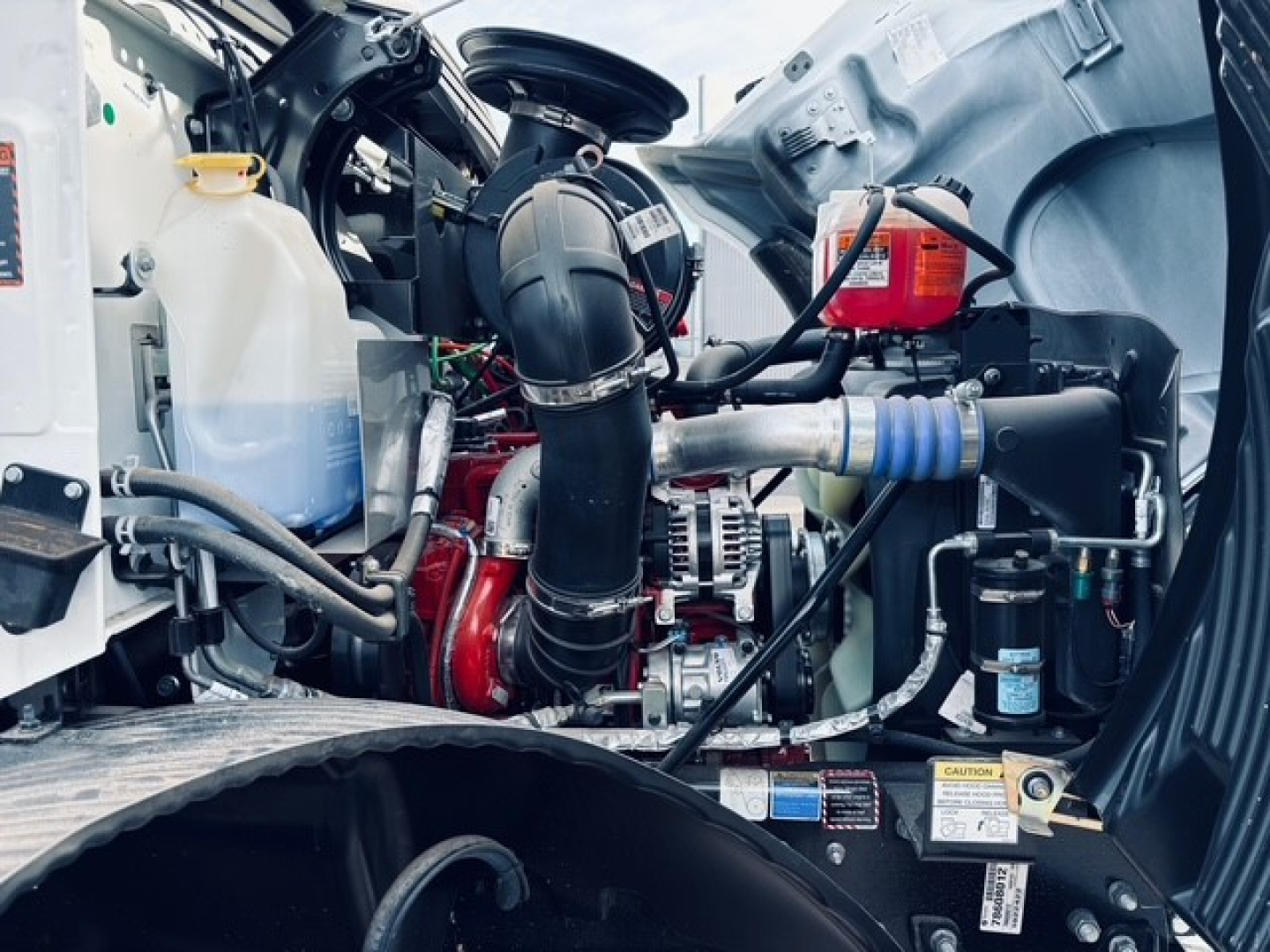 Mack MD6 engine bay showing coolant reservoir, air intake, hoses, and auxiliary components.
