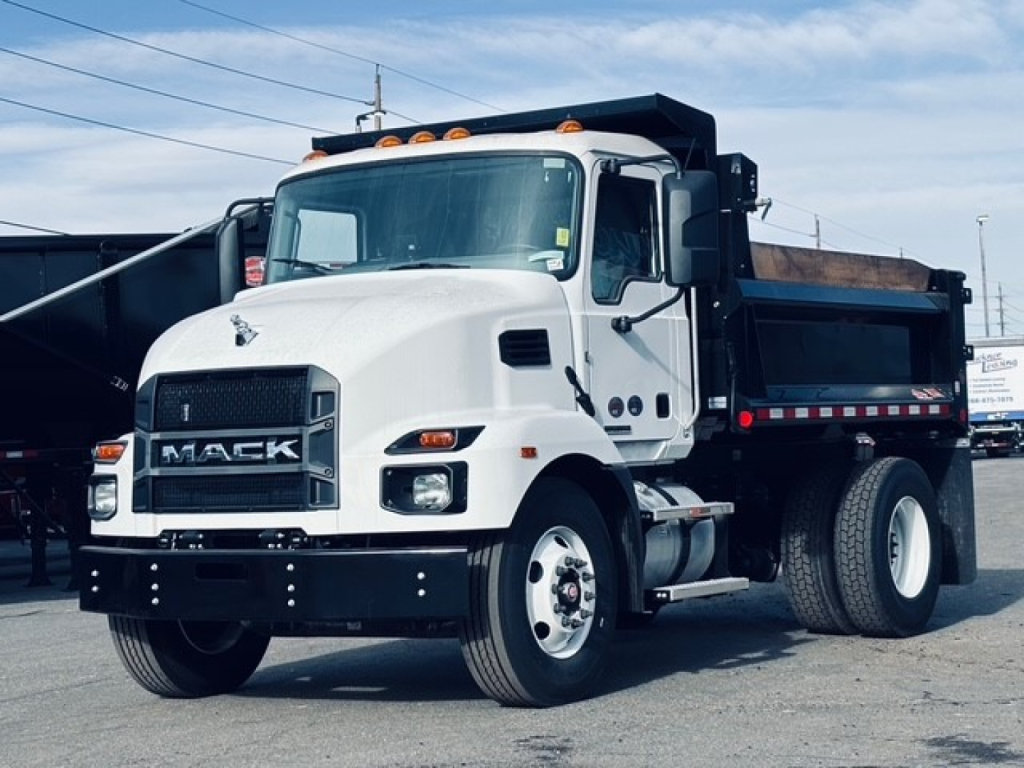 Dump truck front-left view showing Mack MD6 with white cab and black grille, dump bed, and orange marker lights.