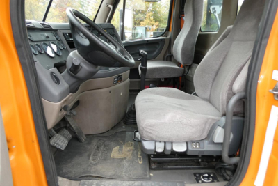 Cab interior of 2013 Freightliner Cascadia 125 daycab showing driver's seat and steering wheel with gauges and pedals.