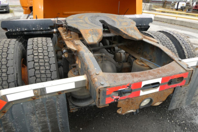 Rear chassis of a Freightliner Cascadia 125 daycab showing the hitch, rail, and mudflap area with visible rust and mounting hardware.