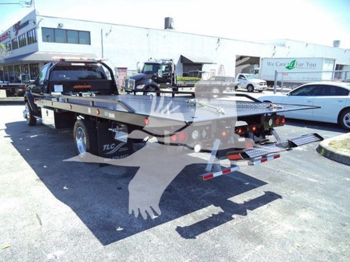 Ram 5500 rollback truck with flatbed showing trailing lights and rear bumper in a dealership lot.