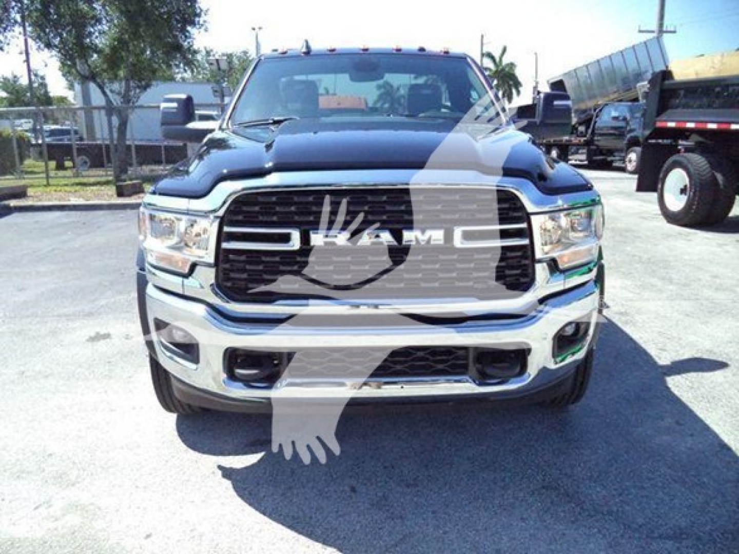 Front view of a dark blue 2024 Ram 5500 SLT pickup truck, large chrome grille with RAM emblem, headlights, chrome bumper, parking lot background.