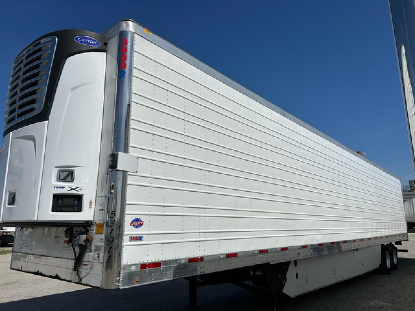 Trailer with Carrier refrigeration unit, white Utility reefer trailer side view showing doors and logo.