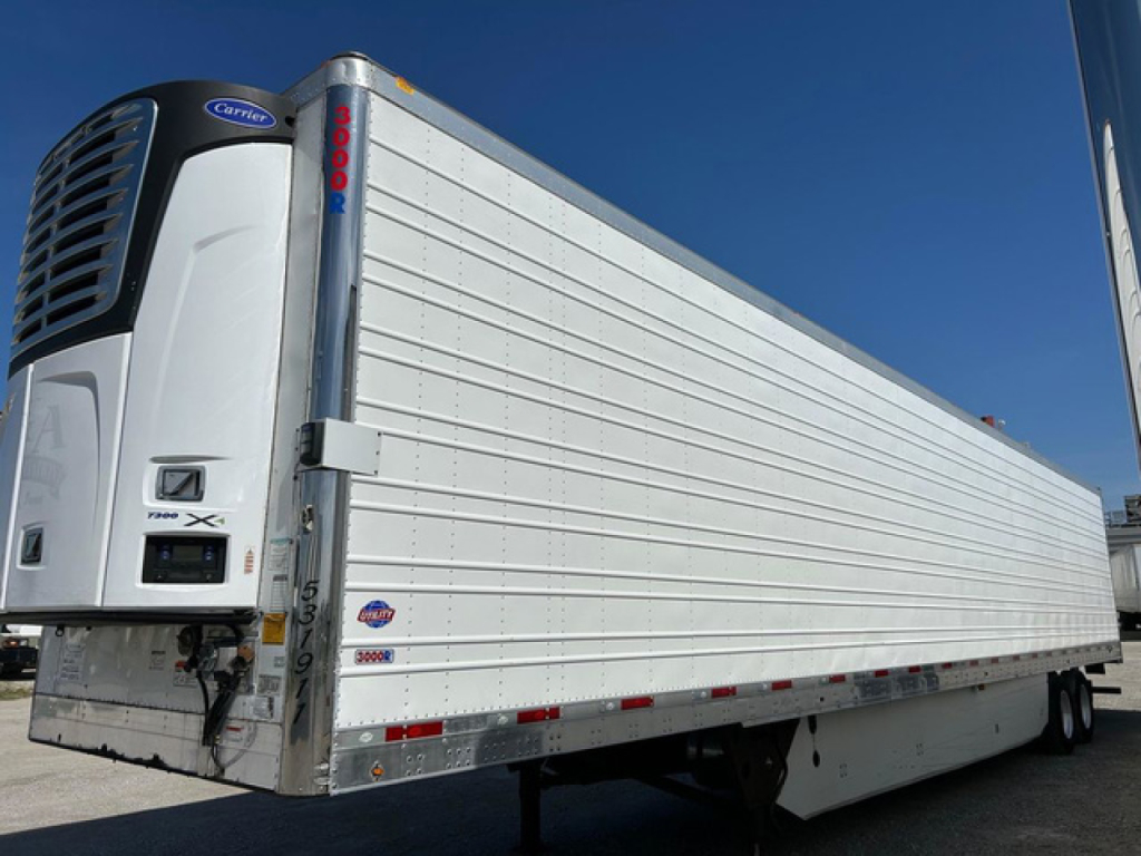 Trailer with Carrier refrigeration unit, white Utility reefer trailer side view showing doors and logo.