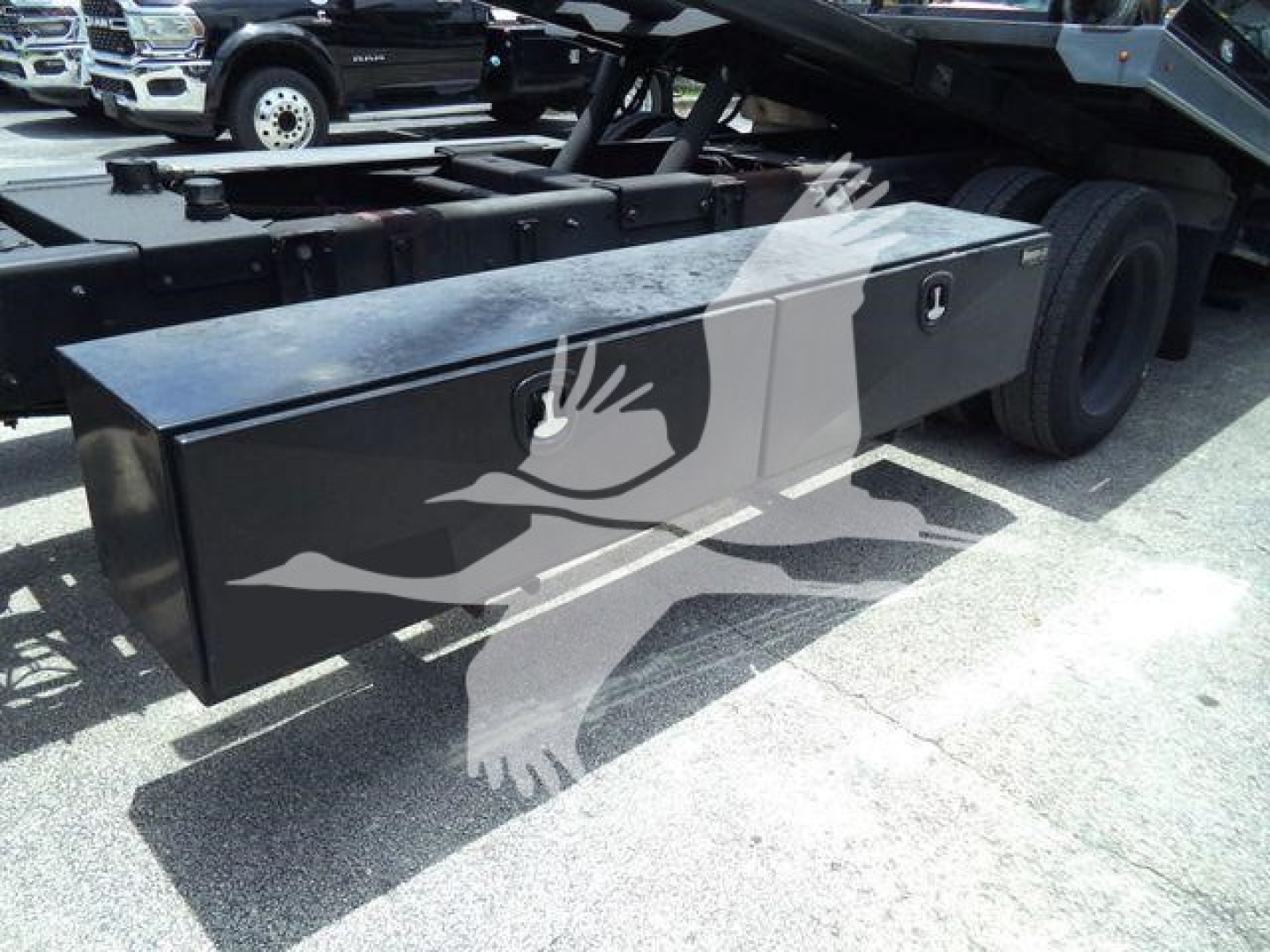 Roll-back truck chassis with a large rectangular aluminum toolbox on the side, two lockable compartments, and dual rear tires visible.
