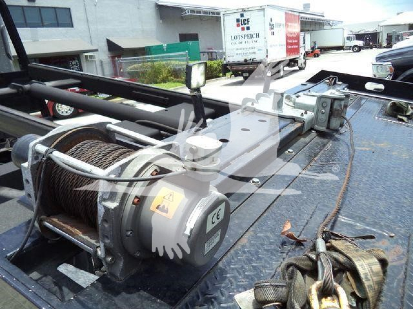Truck equipment showing a winch and reel on the rollback bed with control box and wiring visible.