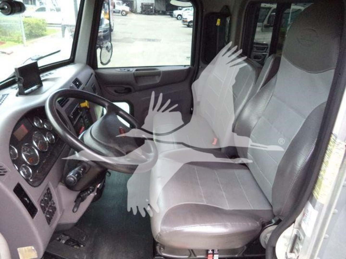 Truck cab interior showing steering wheel, dashboard gauges, driver and passenger seats in Peterbilt 337 listing.