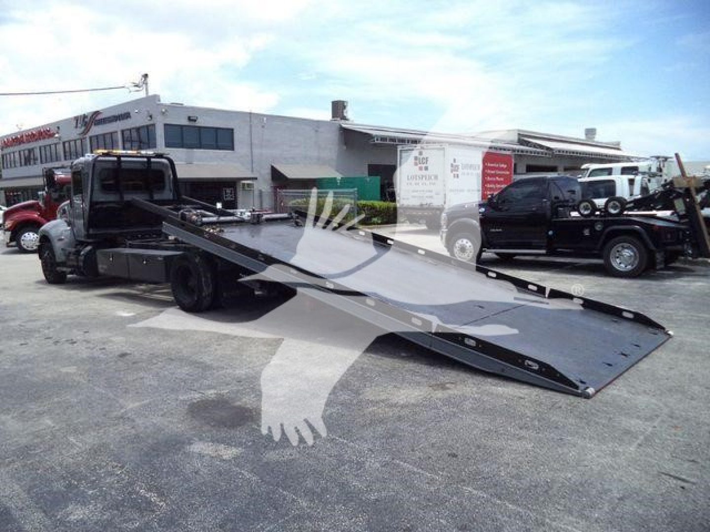 Peterbilt 337 rollback truck with a flatbed tow bed, side view showing the ramped platform extended, rear and side details visible.