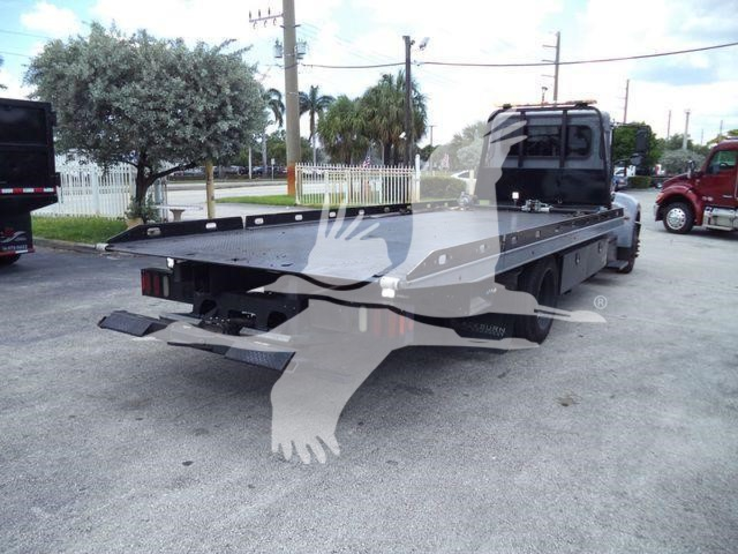Peterbilt 337 rollback truck rear view showing flatbed with wheel lift and cab in background.