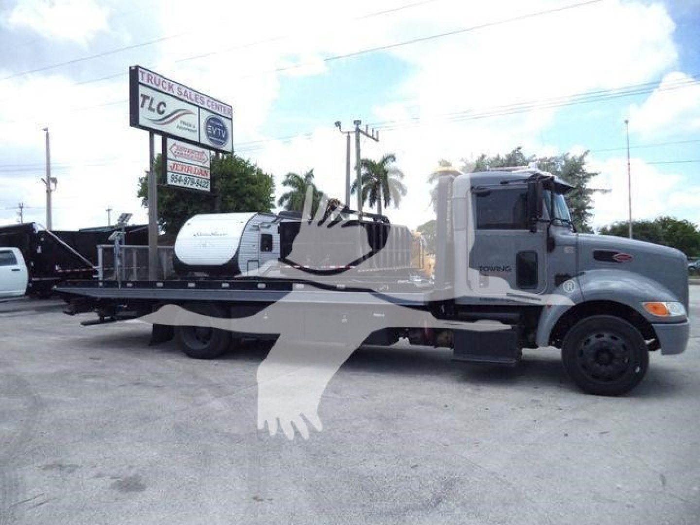 Peterbilt 337 rollback truck side view showing long flatbed and wheel-lift mechanism with cab in gray color.
