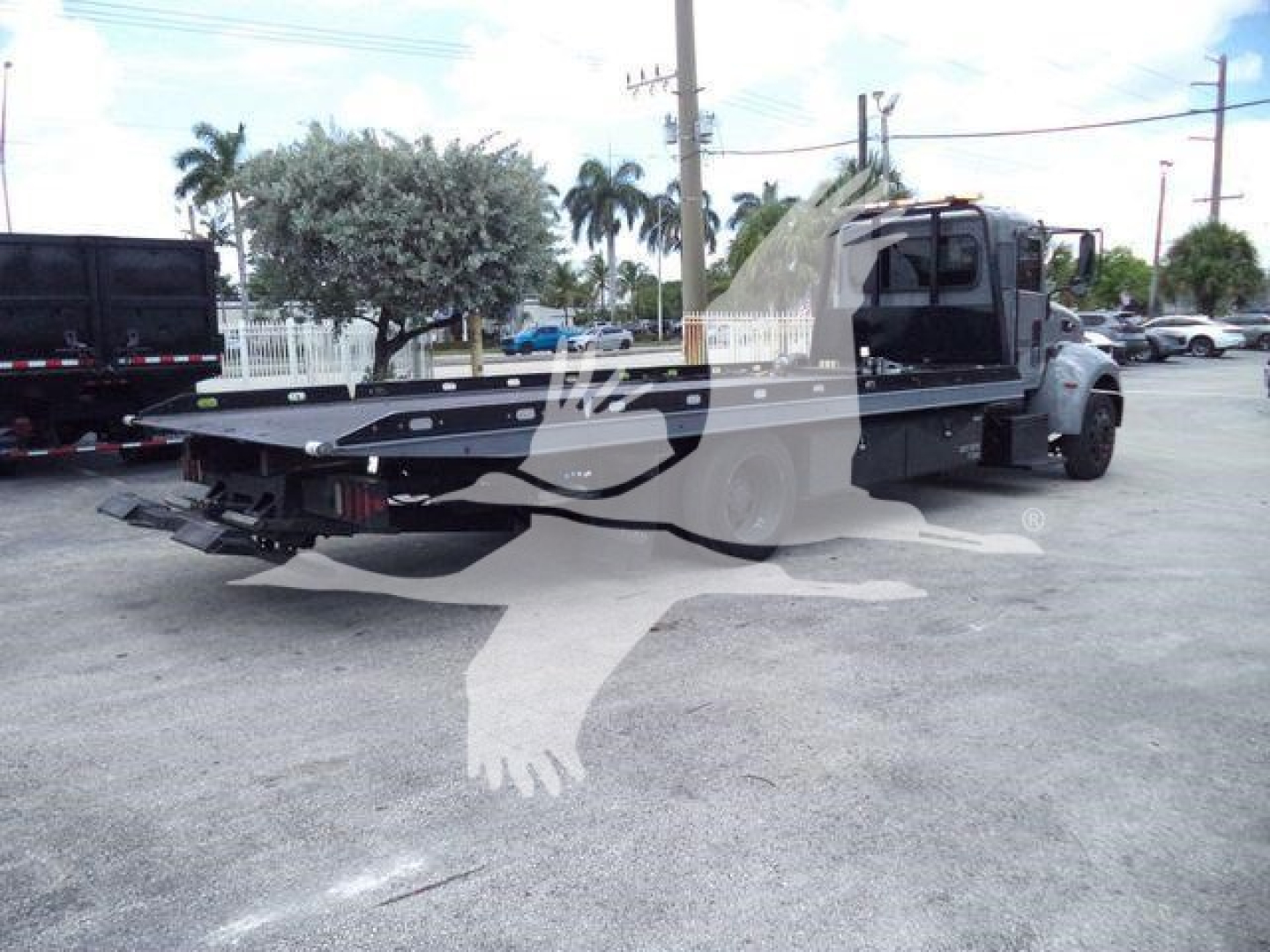 Peterbilt 337 rollback truck side/back view showing flatbed and cab with branding and tail area visible.