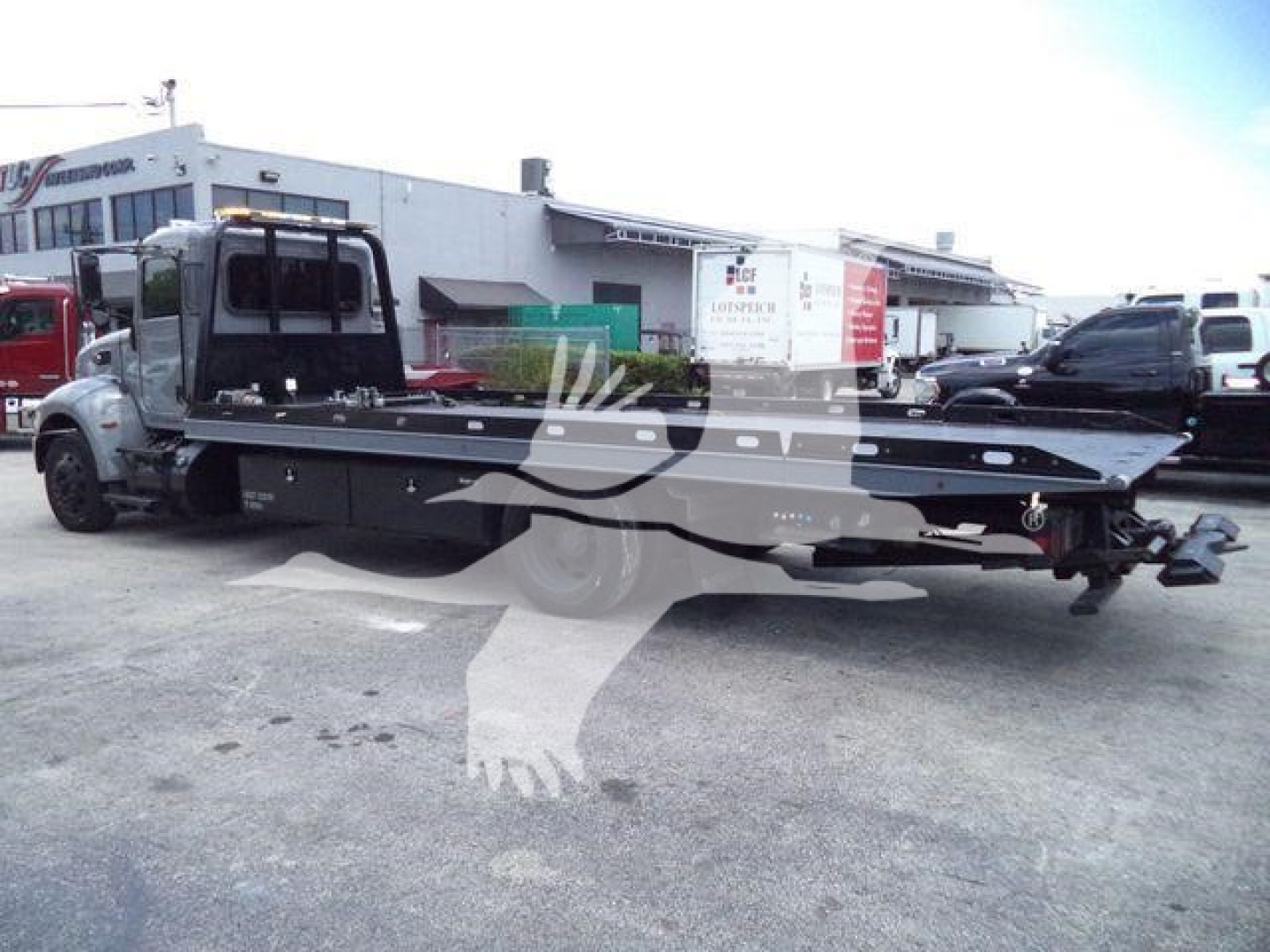 Peterbilt 337 rollback tow truck with long flatbed, side view showing cab, rear hitch, and wheel guards.