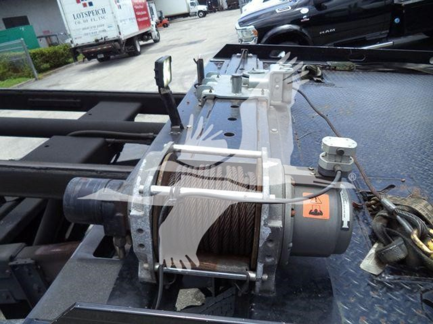 Peterbilt 337 rollback truck area showing winch drum and cable assembly on bed, hoist motor, and hydraulic components.