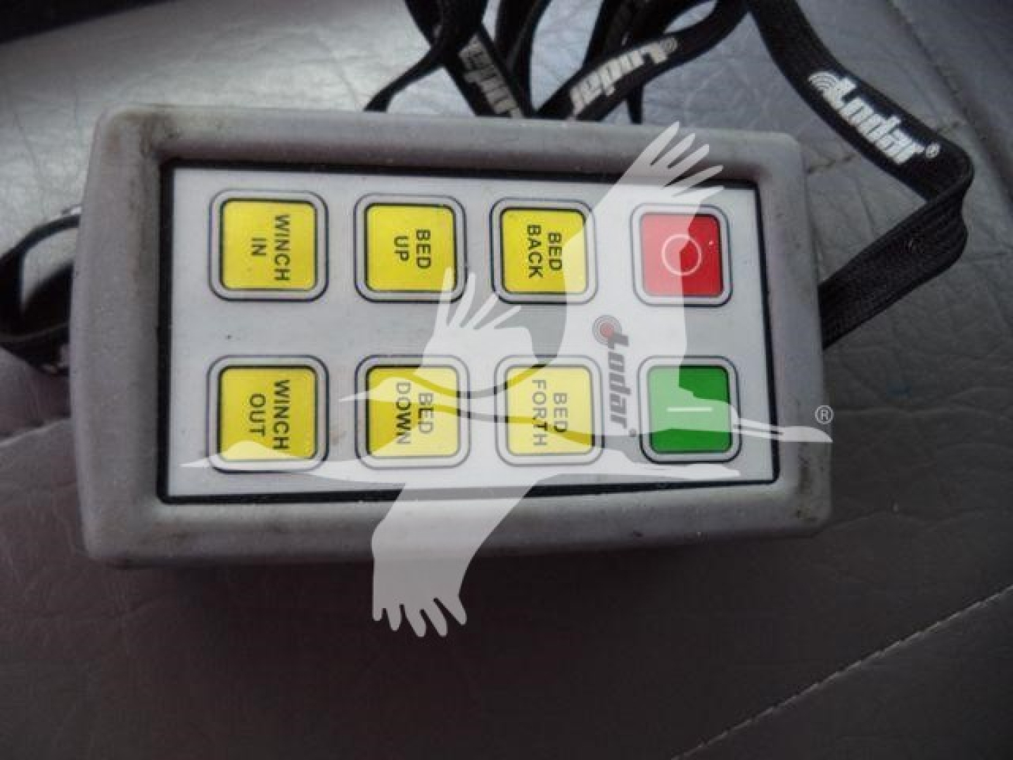 Handheld remote with yellow buttons labeled WINCH IN, WINCH OUT, BED UP, BED DOWN, BED LEFT, BED RIGHT, and a red power button plus a green ok button.