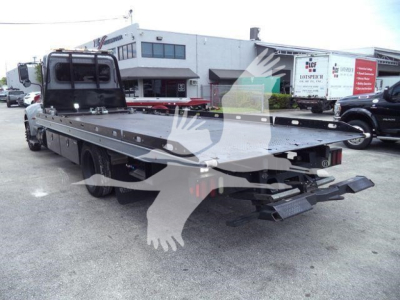 Peterbilt 337 rollback truck flatbed with winch and ramps, side view showing heavy-duty equipment and truck yard.