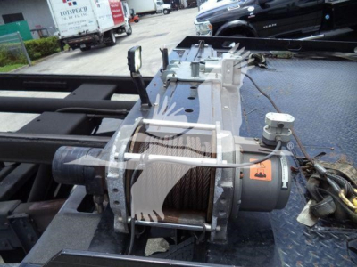 Peterbilt 337 rollback truck area showing winch drum and cable assembly on bed, hoist motor, and hydraulic components.