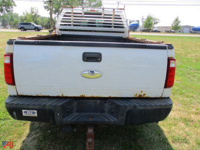 Ford F-250 Super Duty pickup truck tailgate view showing bumper, hitch, and rust spots with metal rack in bed.