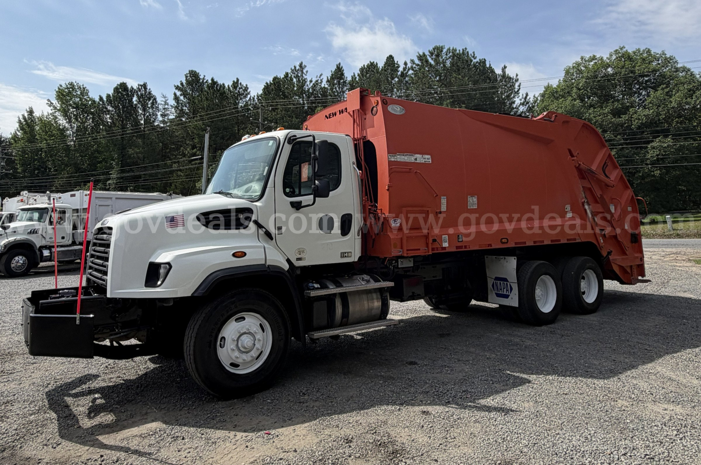 Truck showing a Freightliner 114SD rear hopper garbage body with white cab and orange container, side view with branding and VIN/stock details not visible on the image.
