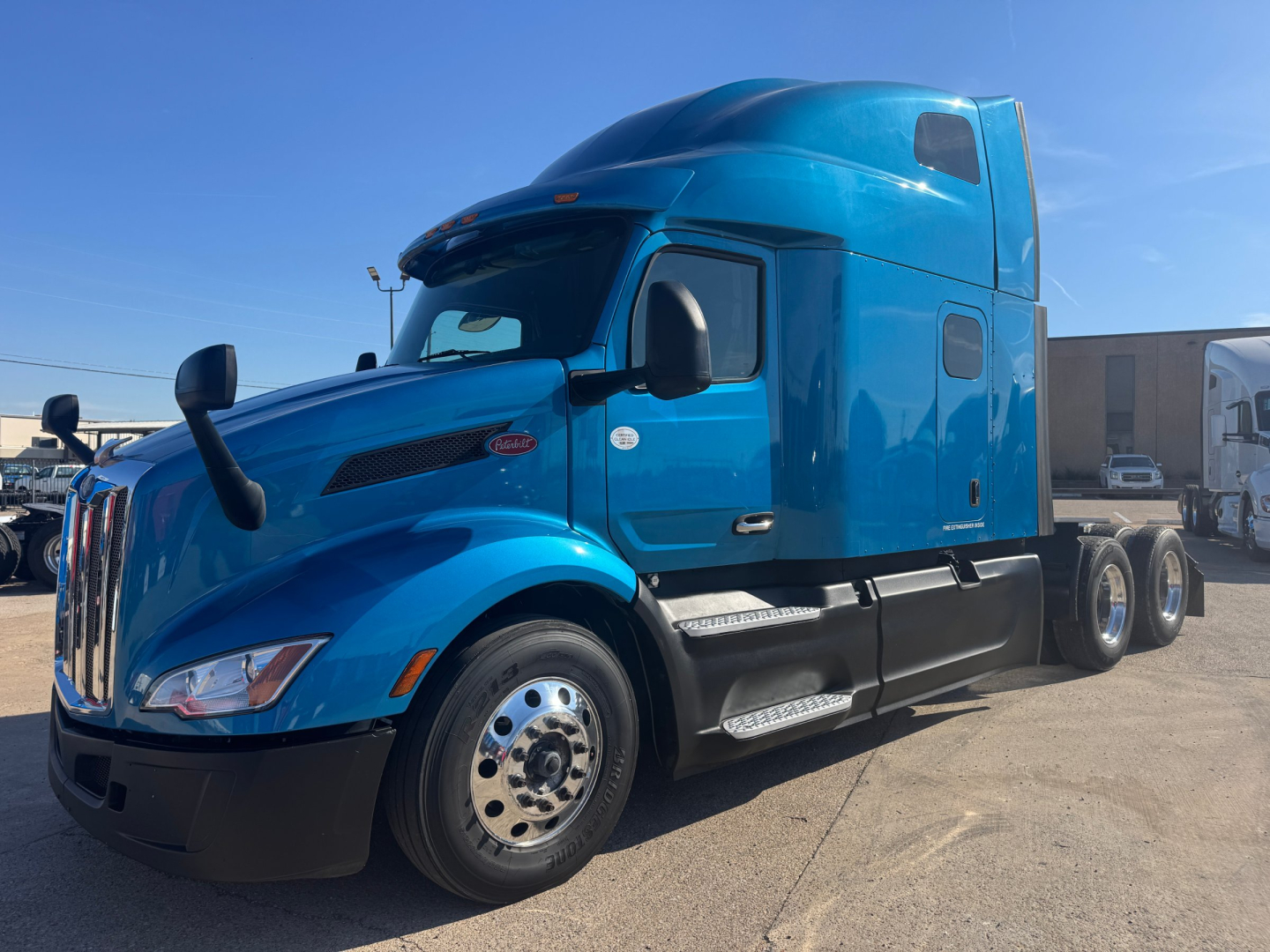 Peterbilt 579 conventional sleeper truck in blue, side view showing cab, chrome wheels, and fuel tanks.