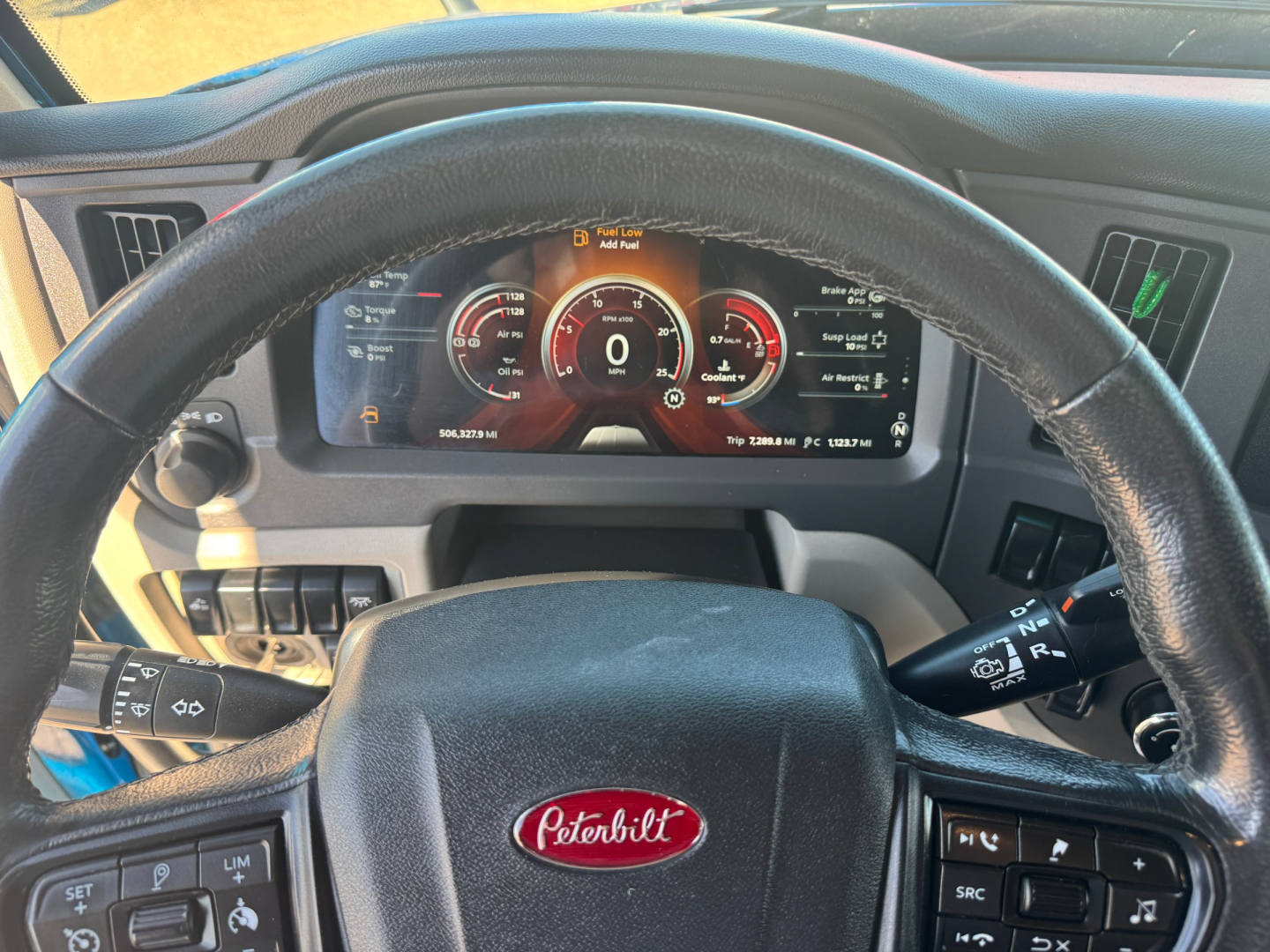 Peterbilt 579 dashboard steering wheel view showing digital instrument cluster and Peterbilt emblem on steering wheel.