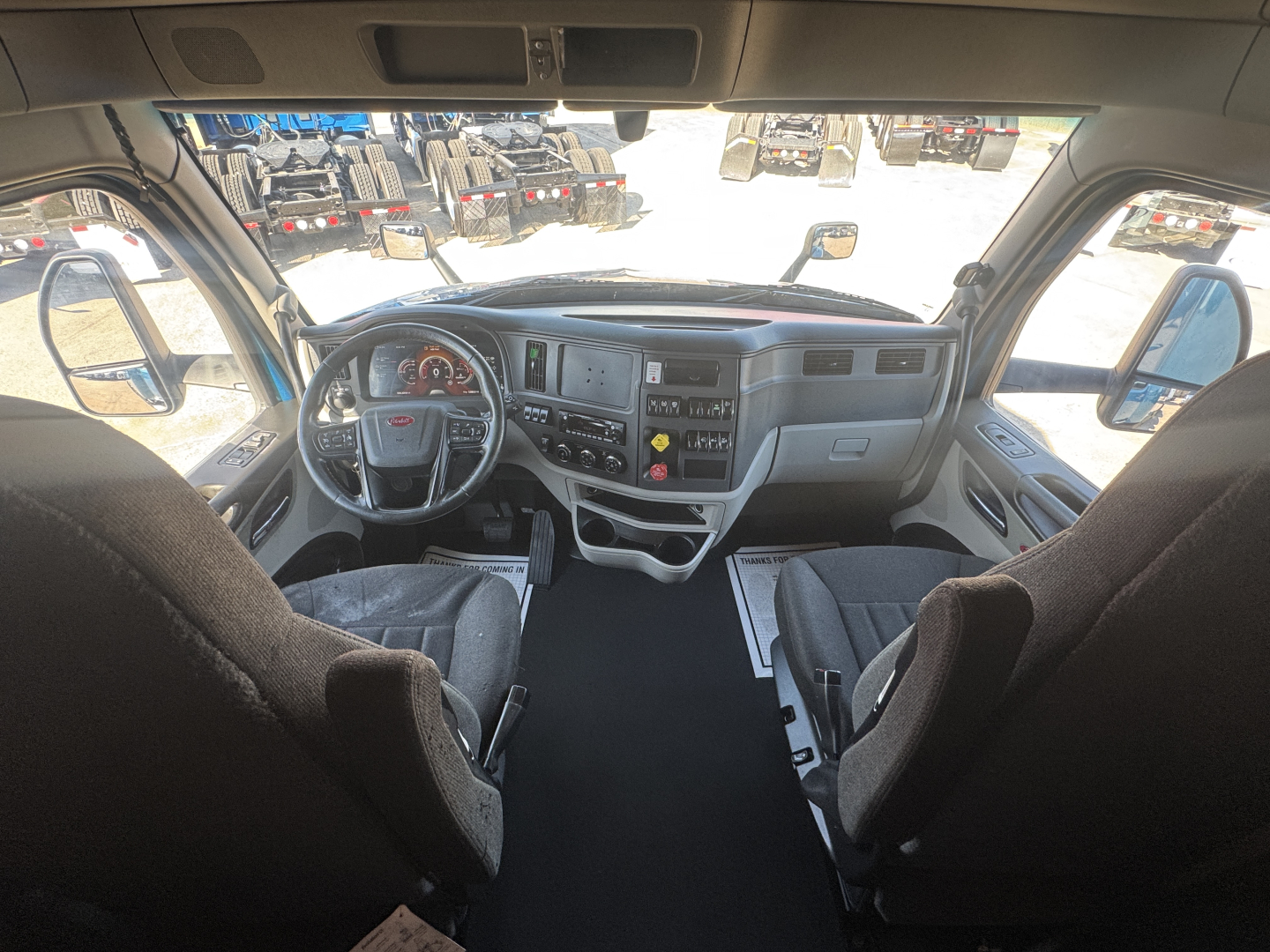 Peterbilt 579 cab interior showing dashboard, steering wheel, and driver seats with center console.