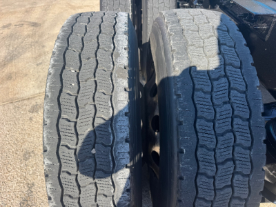 Truck dual rear axles showing treaded tires in close-up view.