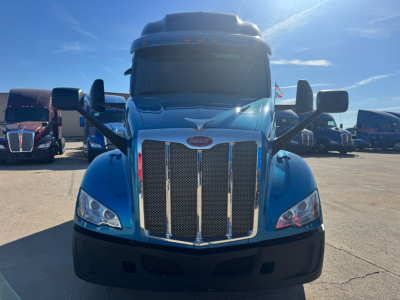 Peterbilt 579 truck front view showing large grille and blue cab with mirrored side mirrors.