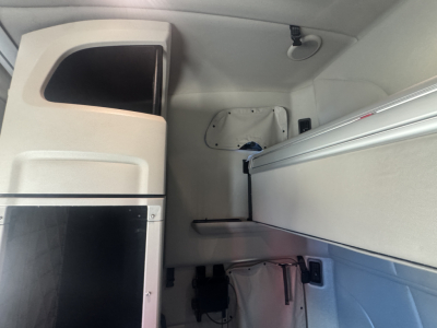 Cab interior of a Peterbilt truck with overhead storage compartments and a bunk area visible. No legible text on parts in the image.