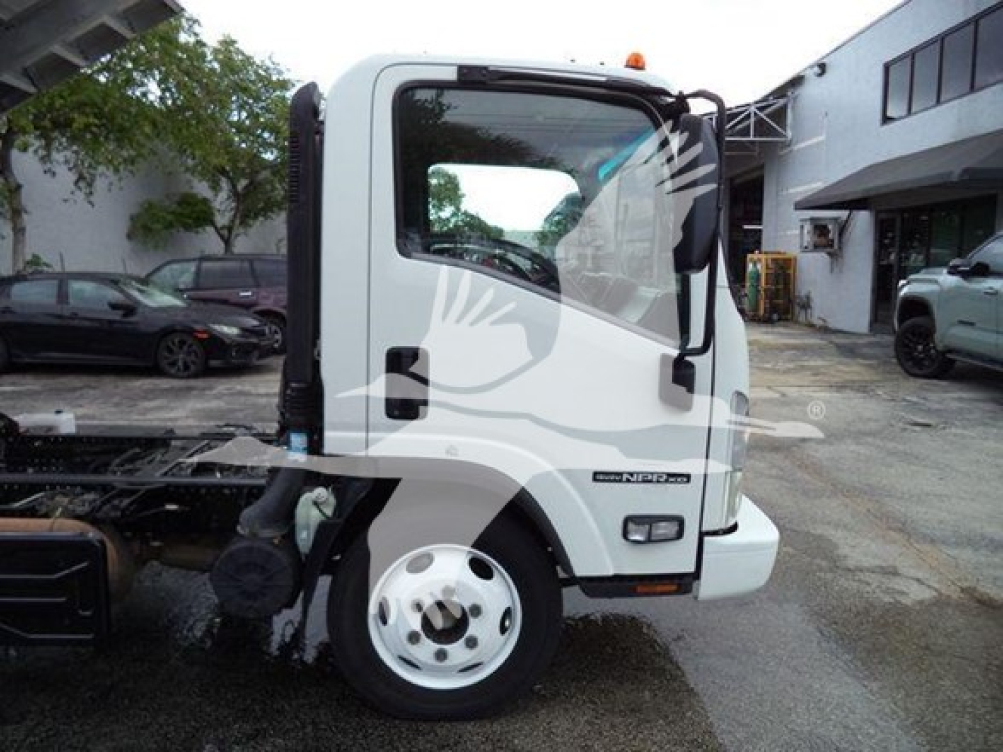 Isuzu NPR-HD cab showing front side with door and wheel, white exterior, chassis visible.