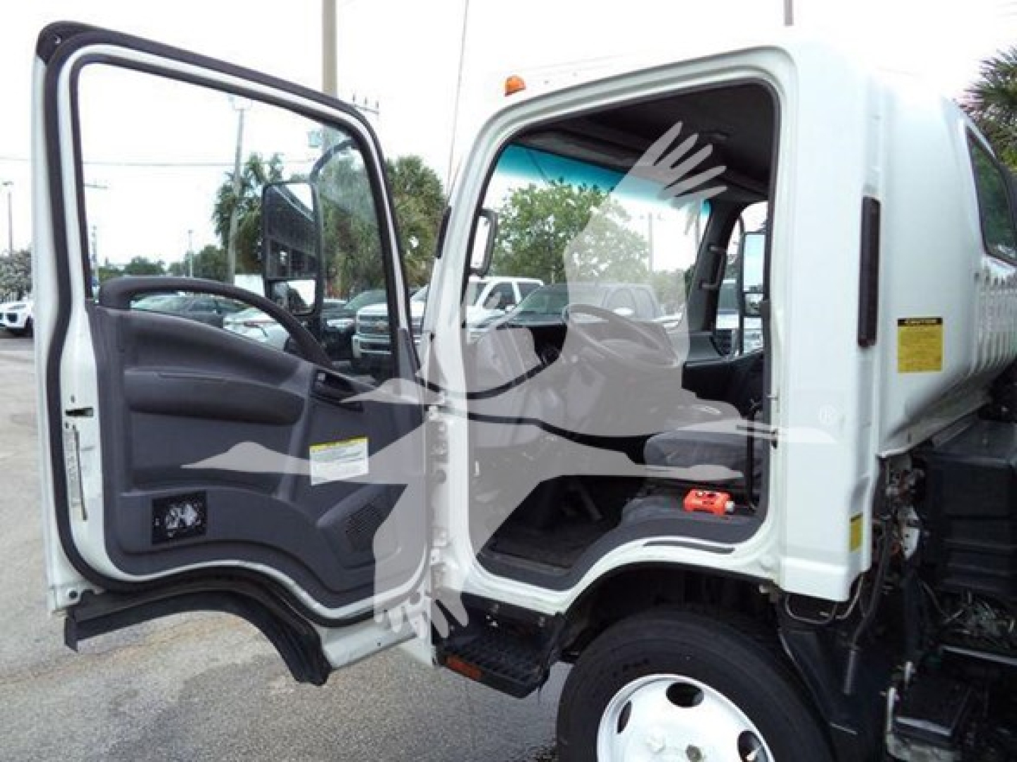 Isuzu NPR XD truck cab interior with open door showing steering wheel and dashboard, white exterior, step, and chassis.