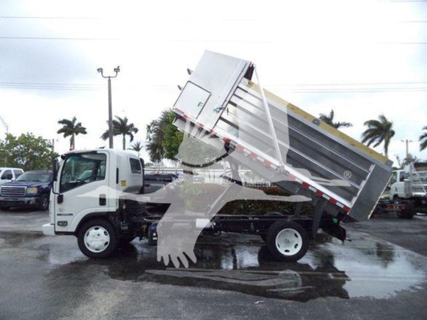 Isuzu NPR XDI dump truck in-service with hydraulic bed raised for dumping.
