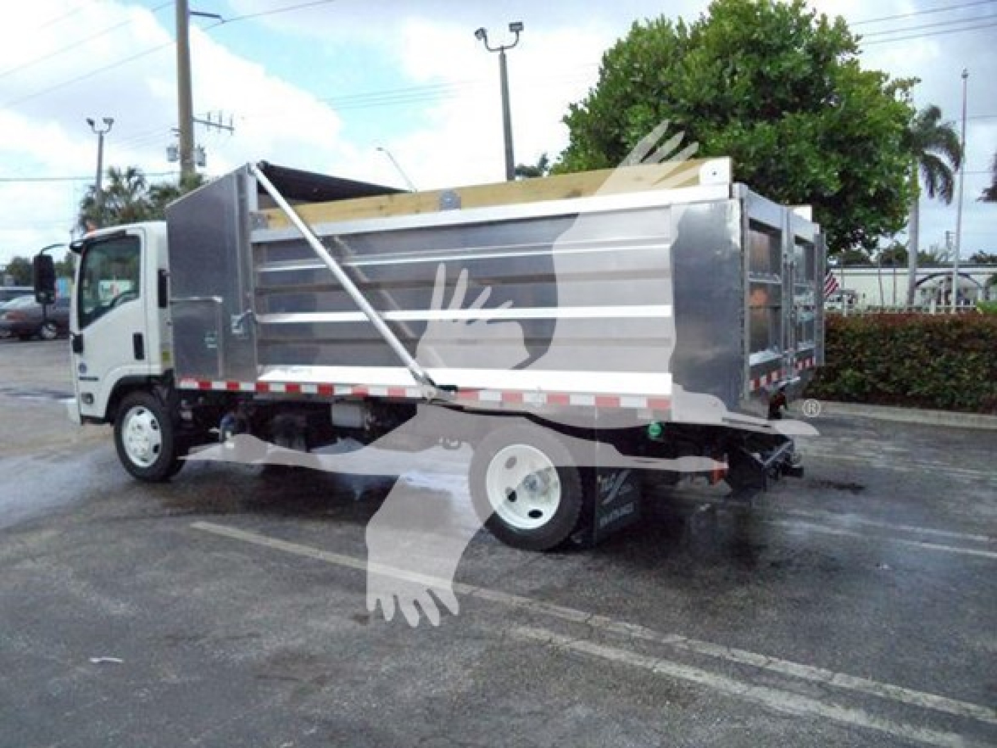 Isuzu NPR XD dump truck side view showing dump bed with metal panels and rear hitch.