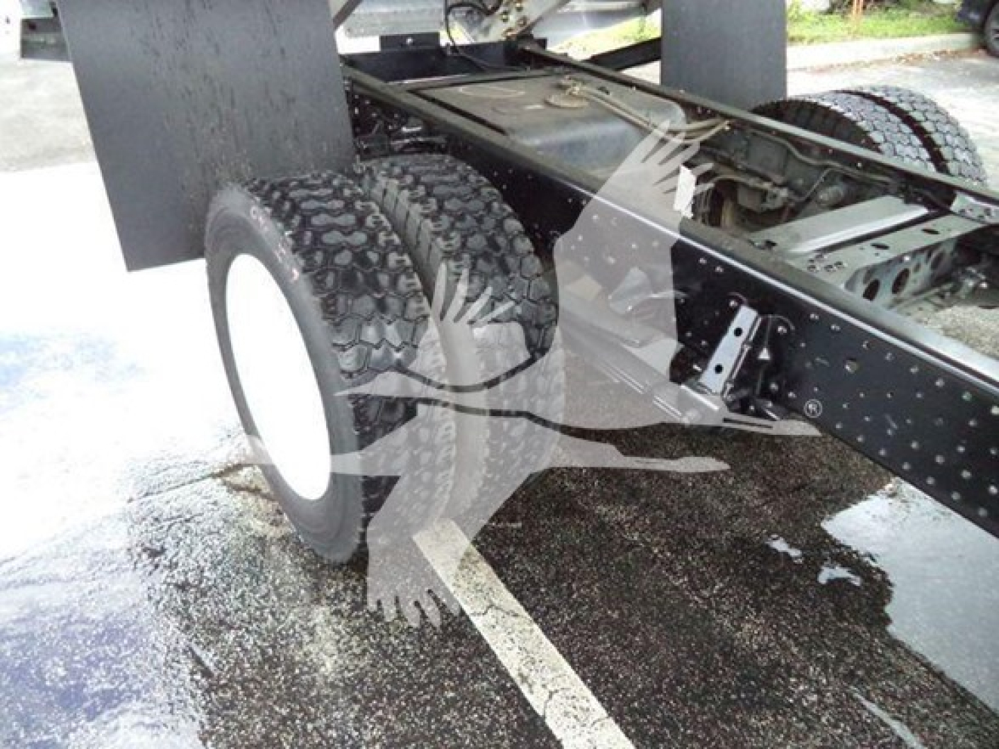 Isuzu NPR XD truck frame and dual rear tires showing undercarriage with chassis rails and suspension components.