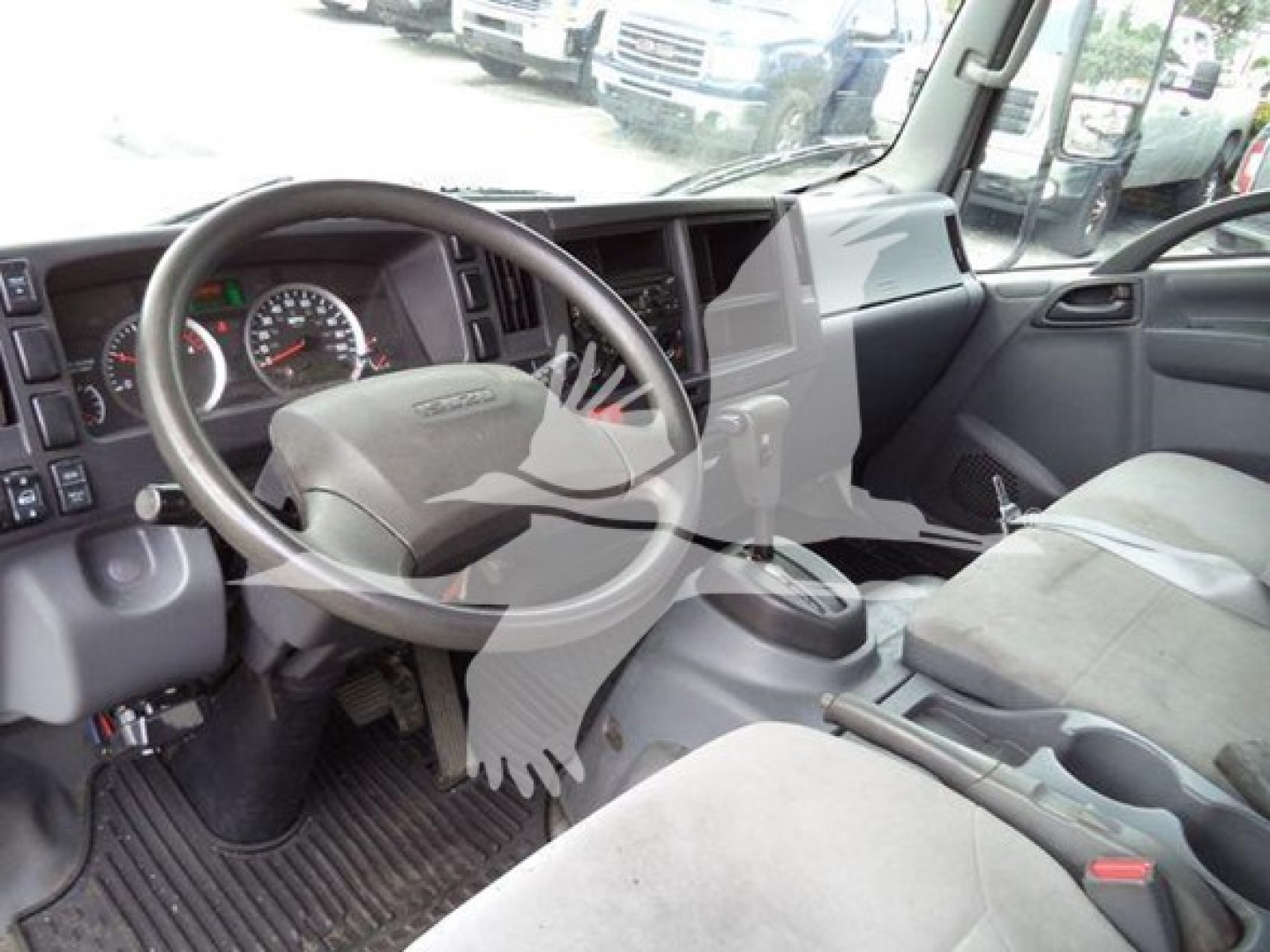 Isuzu NPR XD truck interior showing steering wheel, dashboard, and front seats.
