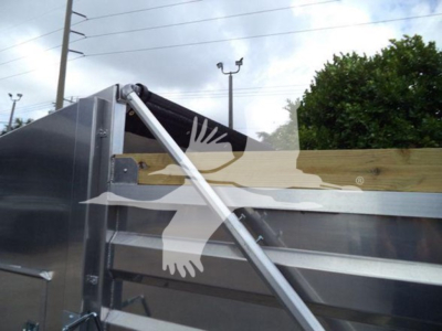 Isuzu NPR XD dump truck in-service showing side view of aluminum dump bed and reinforcement bar.