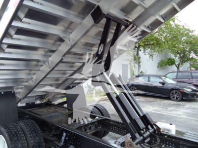 Isuzu NPR XD dump truck chassis and hydraulic lift mechanism under cargo bed showing hydraulic cylinders and steel framework.