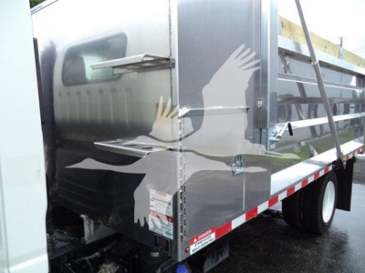 Isuzu NPR XD dump truck side with metal panels and reflective stickers.