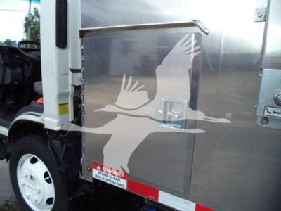 Isuzu NPR XD dump truck side panel with metallic storage box and a bird logo decal visible.